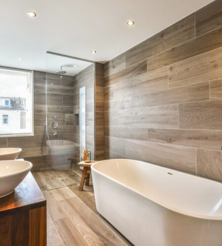 A sleek and modern bathroom showcasing elegant design elements, including a freestanding tub, stylish basin sinks, and contemporary fixtures against a textured tile backdrop.