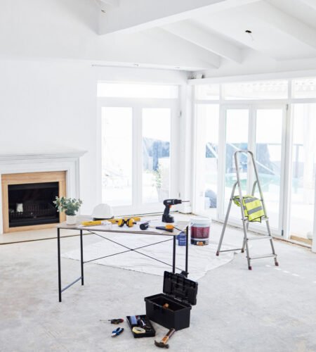 Shot of building plans and equipment on a table in an empty living room during the day.