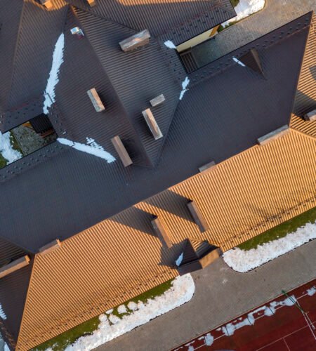 Top aerial view of building brown shingle tiled roof with complex configuration construction. Abstract background, geometrical pattern.